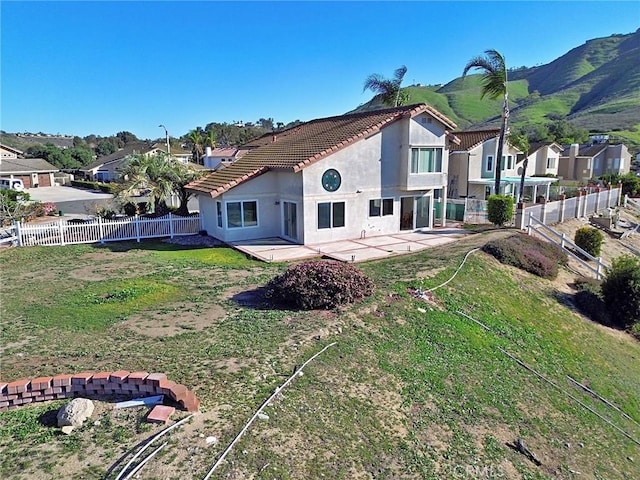 back of house featuring a tile roof, stucco siding, a fenced backyard, a yard, and a patio area