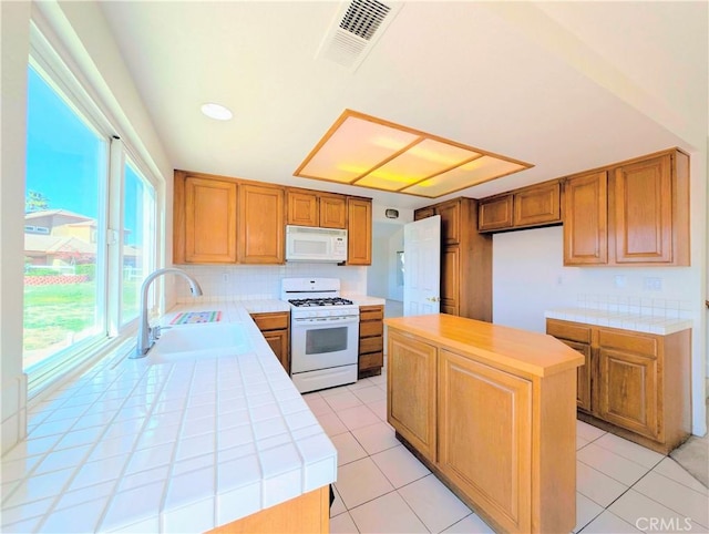 kitchen featuring white appliances, visible vents, tile countertops, and a sink