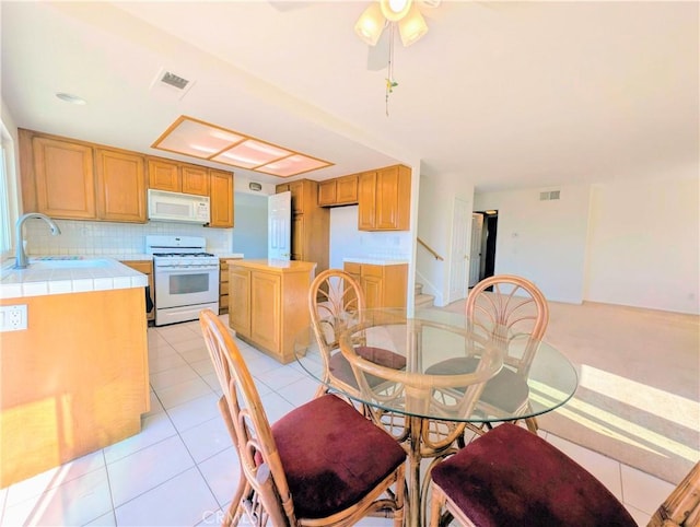 dining space with light tile patterned flooring, visible vents, ceiling fan, and stairway