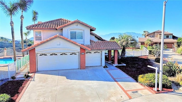 mediterranean / spanish home with concrete driveway, stucco siding, fence, a tiled roof, and a garage