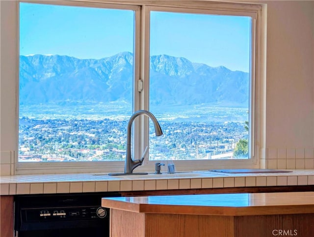 interior details with black dishwasher, tile countertops, and a mountain view