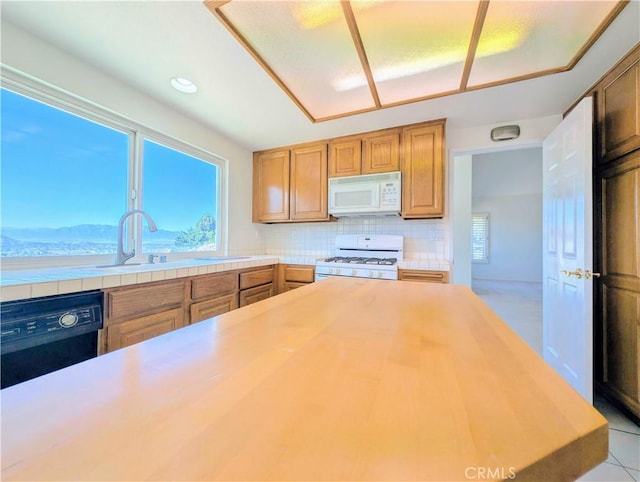 kitchen featuring white appliances, backsplash, a sink, and a healthy amount of sunlight