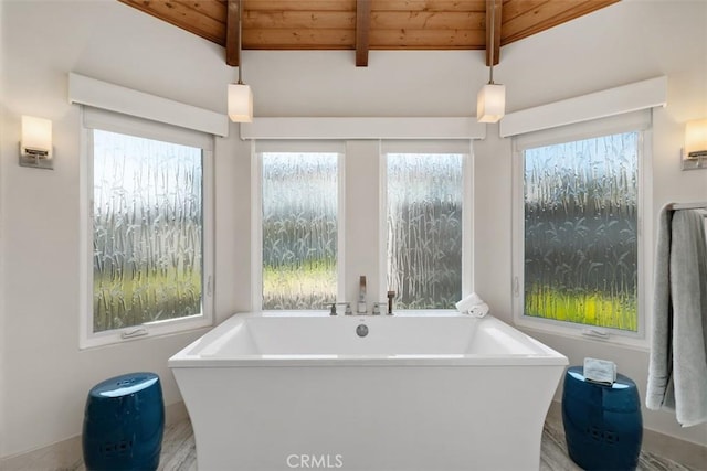 full bath with beamed ceiling, wooden ceiling, a freestanding tub, and a healthy amount of sunlight
