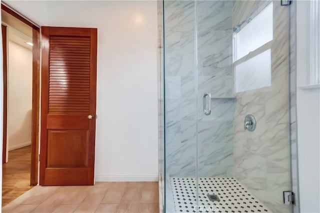 full bath with baseboards, a marble finish shower, and wood finished floors