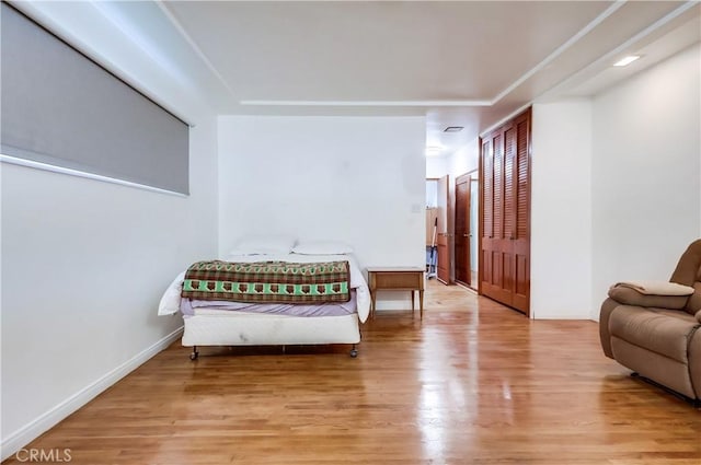 bedroom featuring a closet, light wood finished floors, and baseboards