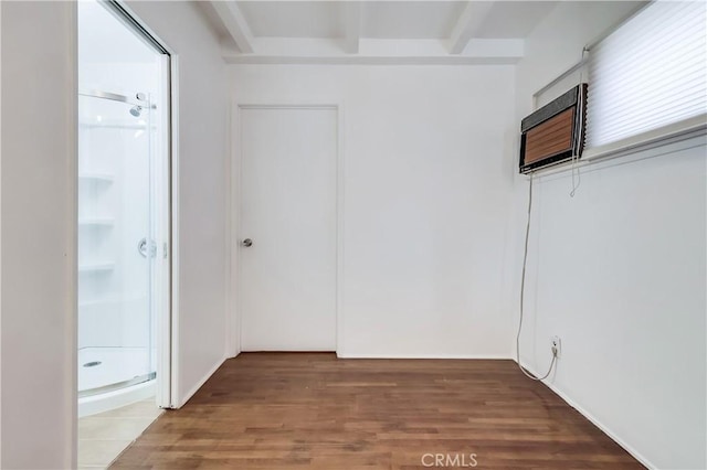 unfurnished room with beamed ceiling, wood finished floors, and a wall mounted air conditioner