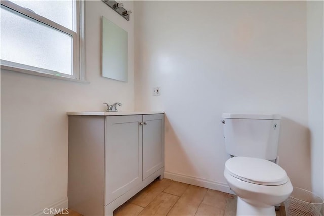 bathroom with toilet, wood finished floors, vanity, and baseboards