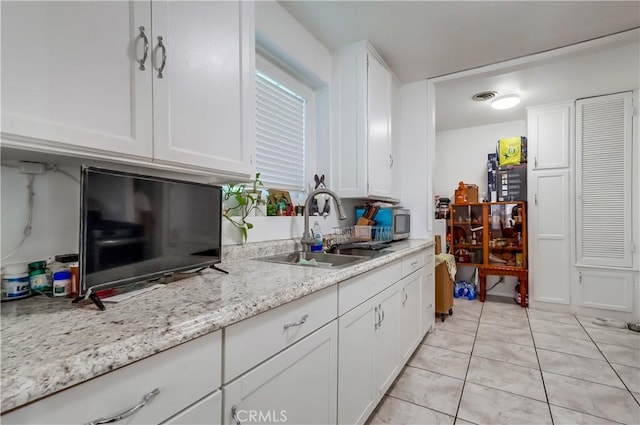 kitchen featuring light tile patterned floors, white cabinetry, and a sink