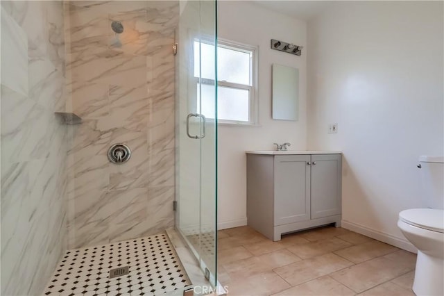bathroom with a marble finish shower, toilet, vanity, and baseboards