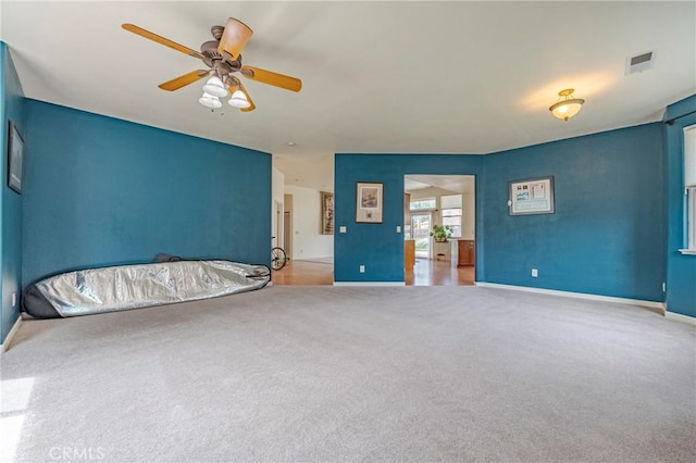 carpeted spare room with baseboards, ceiling fan, and visible vents