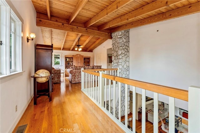 corridor with wooden ceiling, baseboards, wood finished floors, lofted ceiling with beams, and an upstairs landing