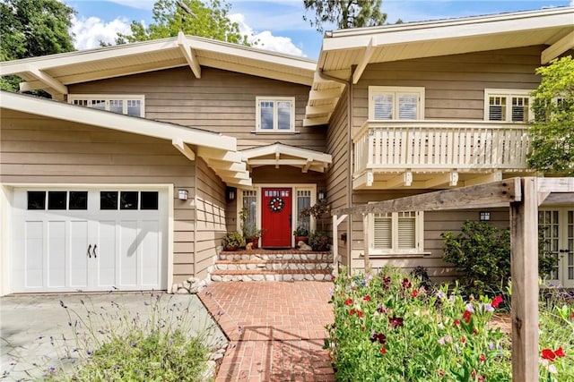 view of front of house featuring driveway, a garage, and a balcony