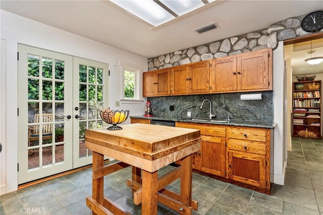kitchen with a sink, french doors, visible vents, decorative backsplash, and dark countertops