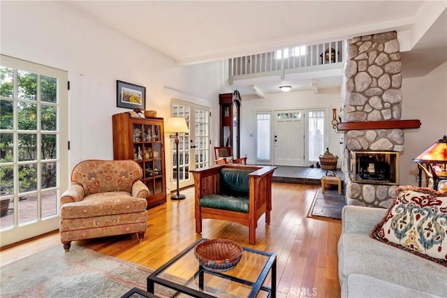 living area featuring a wealth of natural light, french doors, a fireplace, and hardwood / wood-style flooring