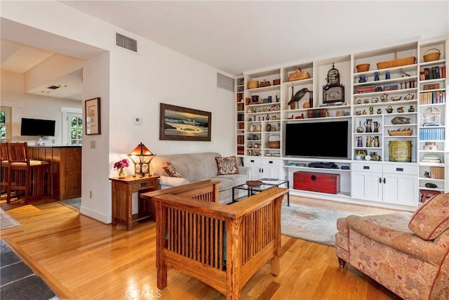 living area with light wood-style floors and visible vents
