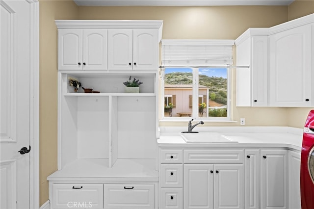 laundry room with cabinet space, washer / dryer, and a sink