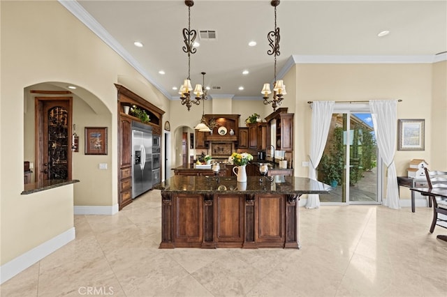 kitchen with arched walkways, built in refrigerator, visible vents, and crown molding
