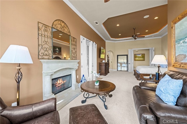 carpeted living area featuring a glass covered fireplace, crown molding, a ceiling fan, and recessed lighting