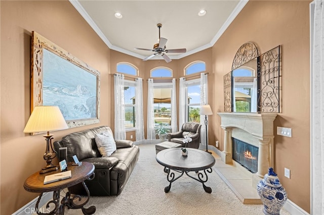 living room with baseboards, a ceiling fan, a glass covered fireplace, and ornamental molding