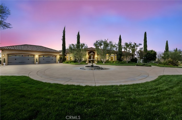 mediterranean / spanish-style home with a tiled roof, a front lawn, curved driveway, and stucco siding
