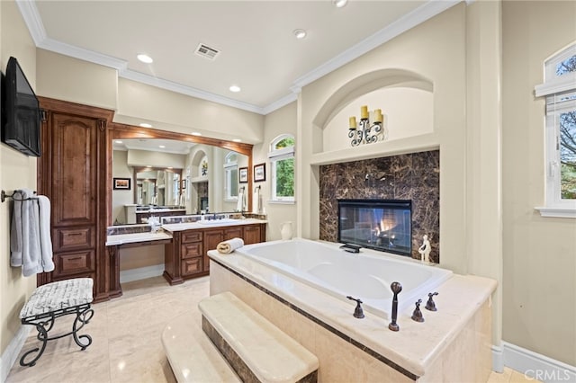 bathroom with visible vents, vanity, crown molding, a fireplace, and a garden tub