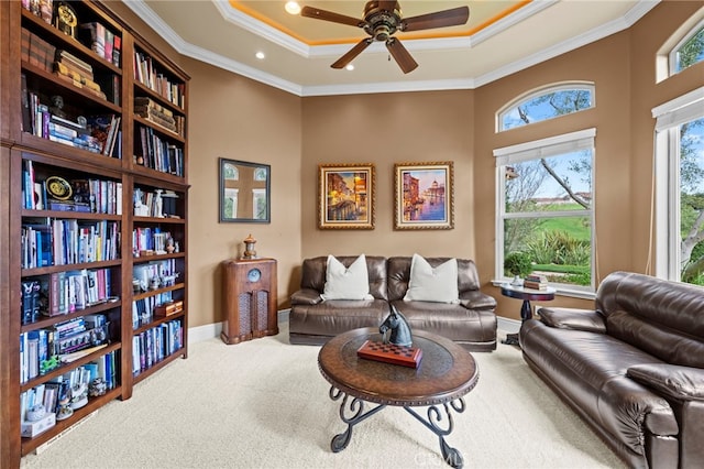 living area with a tray ceiling, baseboards, carpet, a ceiling fan, and ornamental molding