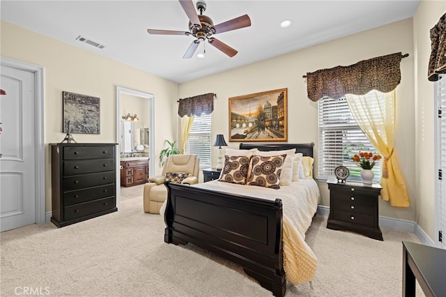 bedroom with ensuite bathroom, visible vents, light colored carpet, and multiple windows