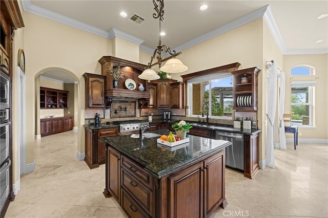 kitchen with an island with sink, visible vents, arched walkways, tasteful backsplash, and appliances with stainless steel finishes