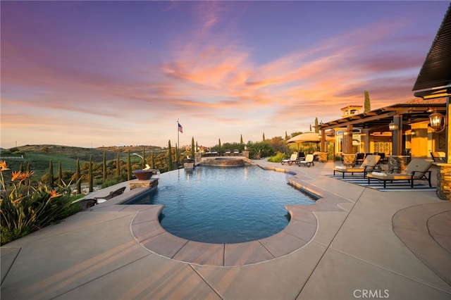 pool at dusk featuring a patio area and a pool with connected hot tub