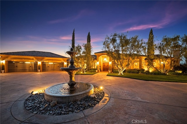 mediterranean / spanish-style house featuring stucco siding, a tiled roof, and curved driveway