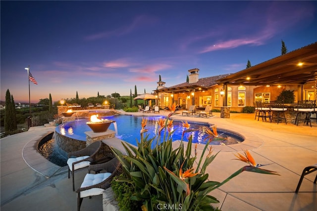 pool at dusk with an outdoor pool, a patio, and outdoor dry bar