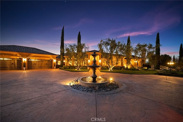mediterranean / spanish-style house with a garage, a tiled roof, and curved driveway