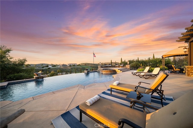 pool at dusk with a gazebo, a patio area, and a pool with connected hot tub