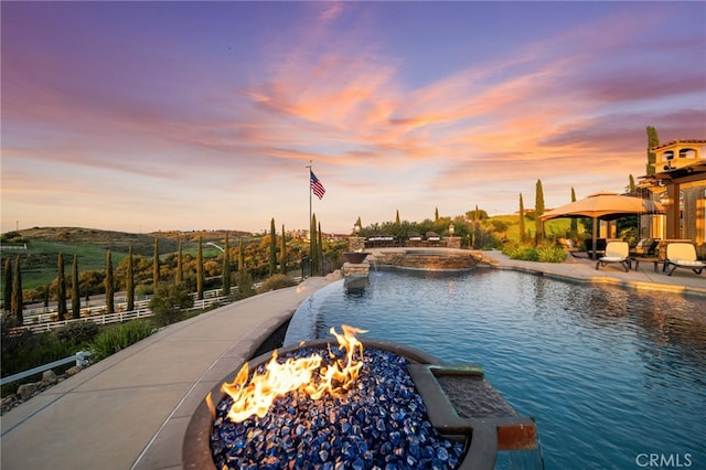view of pool featuring a patio, a pool with connected hot tub, and a fire pit