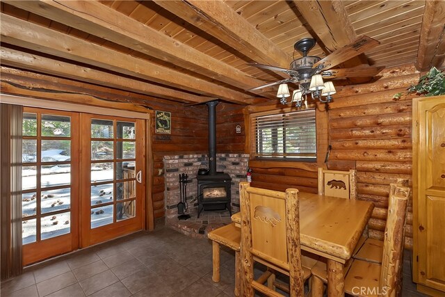 2424 Spruce Dr, Running Springs, CA 92382 - dining space featuring a wood ceiling with exposed beams, a wood stove, dark tile patterned flooring, a ceiling fan, and french doors