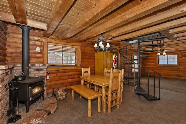 2424 Spruce Dr, Running Springs, CA 92382 - dining space with a wood stove, log walls, ceiling fan, stairway, and wooden ceiling with exposed beams
