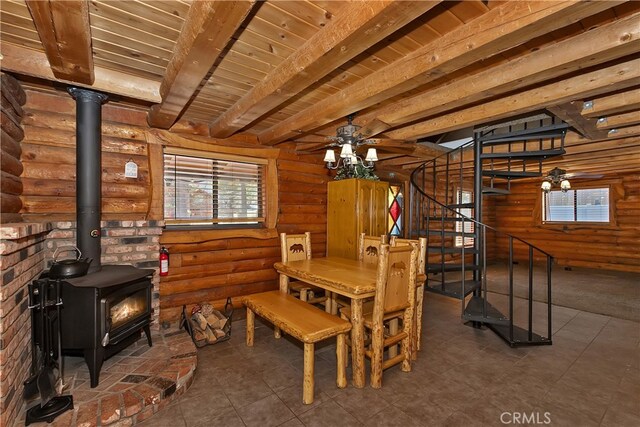 2424 Spruce Dr, Running Springs, CA 92382 - tiled dining area featuring a wood stove, rustic walls, stairway, a ceiling fan, and a wood ceiling with exposed beams
