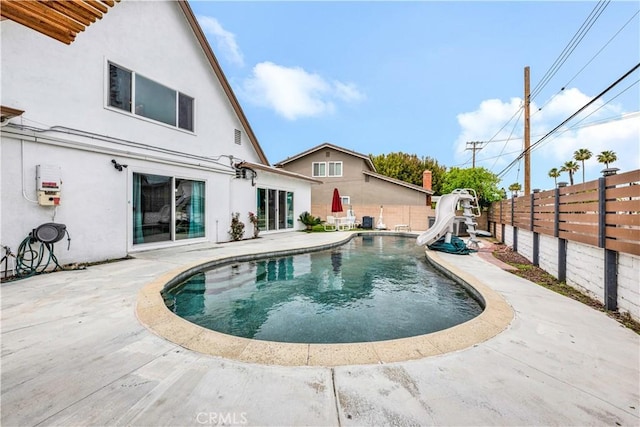 view of pool with a fenced in pool, a fenced backyard, a water slide, and a patio area