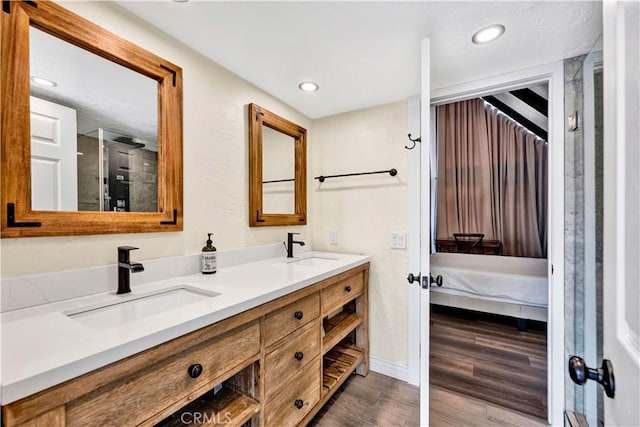 bathroom featuring double vanity, wood finished floors, ensuite bathroom, and a sink
