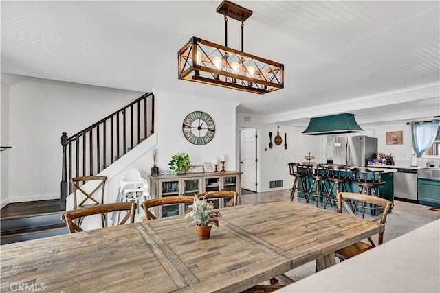 dining room featuring a chandelier, light wood finished floors, visible vents, and stairway