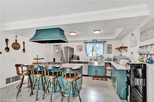 kitchen featuring light countertops, exhaust hood, visible vents, appliances with stainless steel finishes, and green cabinetry