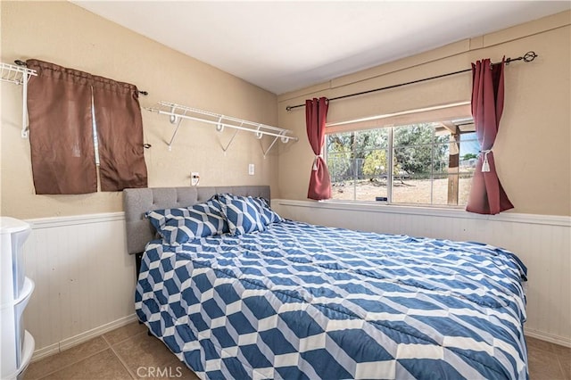 tiled bedroom featuring a wainscoted wall