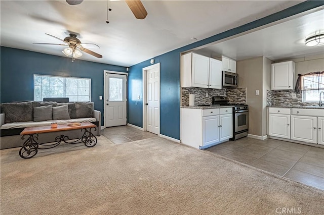 kitchen with white cabinetry, light colored carpet, backsplash, ceiling fan, and appliances with stainless steel finishes