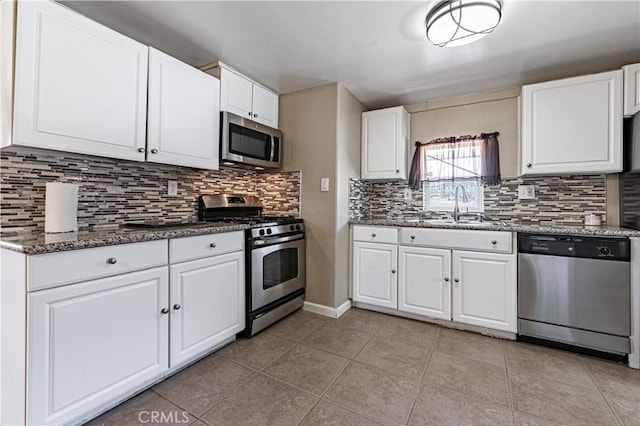 kitchen with light tile patterned flooring, a sink, backsplash, white cabinetry, and appliances with stainless steel finishes