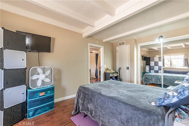 bedroom with a closet, visible vents, beamed ceiling, baseboards, and wood finished floors