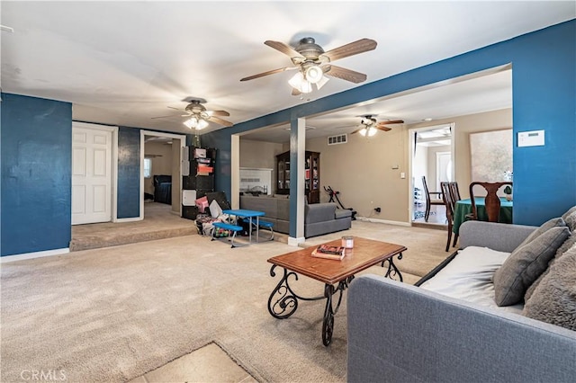 living area featuring baseboards, visible vents, ceiling fan, and carpet floors