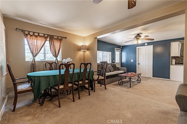 dining space featuring baseboard heating, light colored carpet, and ceiling fan