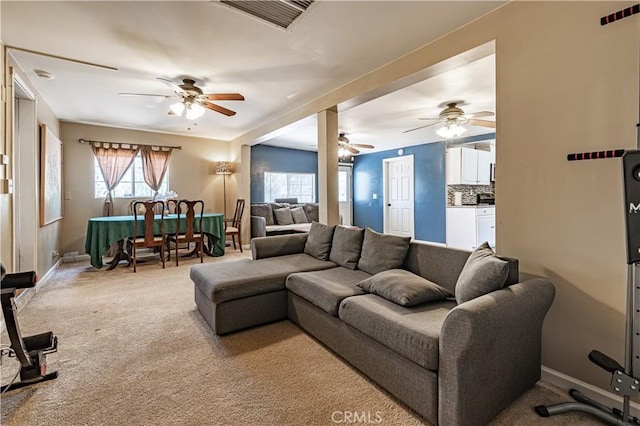 living room with light carpet, visible vents, and ceiling fan