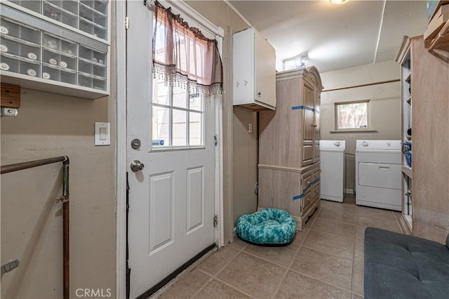 clothes washing area featuring washing machine and clothes dryer, cabinet space, a wealth of natural light, and light tile patterned floors