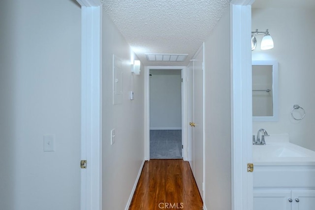 23222 Orange Ave Unit 4, Lake Forest, CA 92630 - hallway featuring a textured ceiling, visible vents, a sink, baseboards, and dark wood-style floors